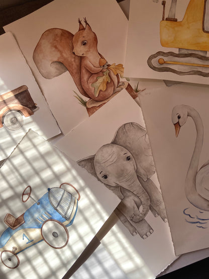 A collection of hand-drawn watercolor illustrations on paper, featuring a brown squirrel, a gray elephant, a white swan, a blue and white toy car, and a yellow vehicle, arranged on a surface with dappled sunlight.